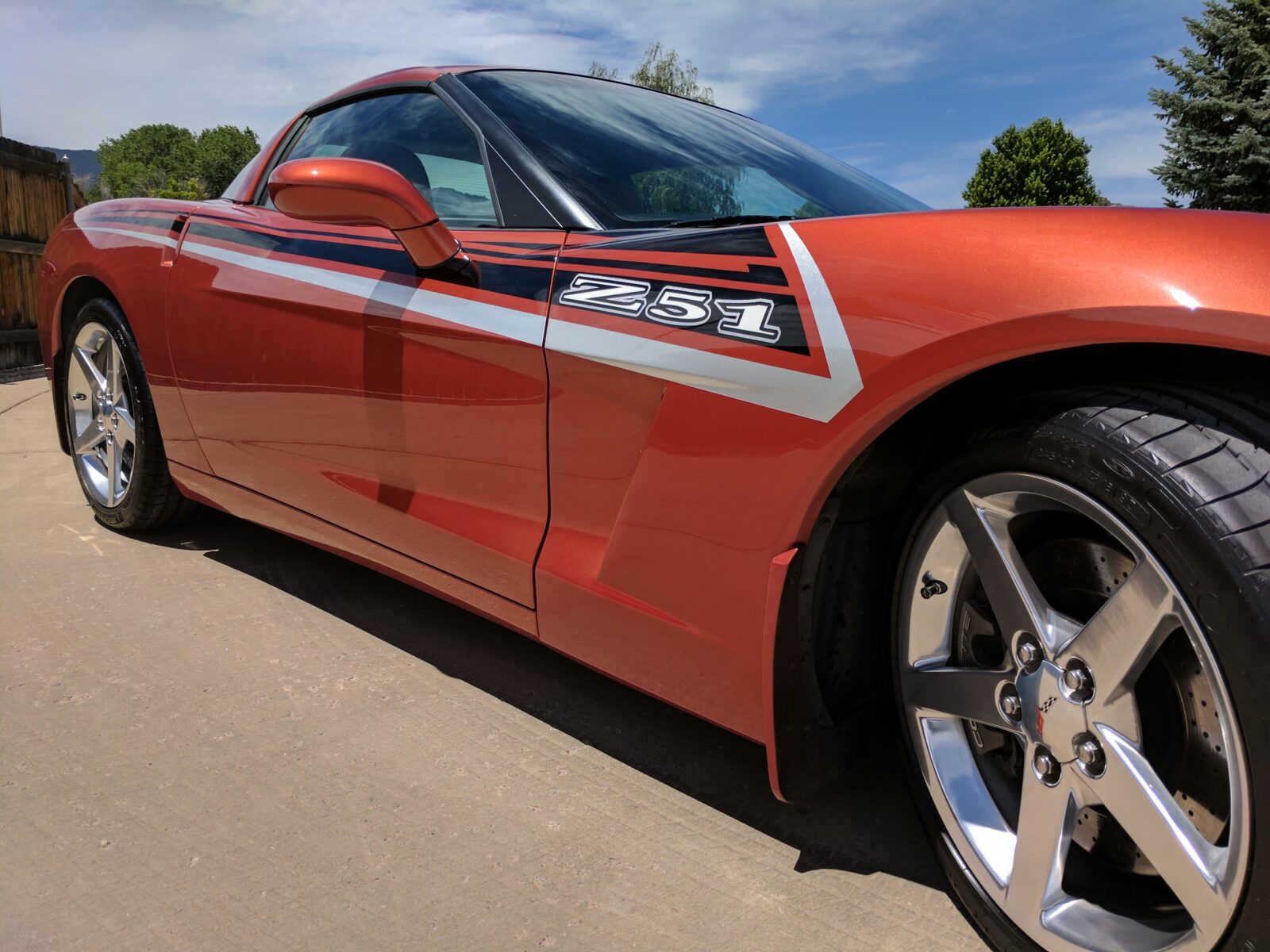 A red sports car with chrome wheels on the street.